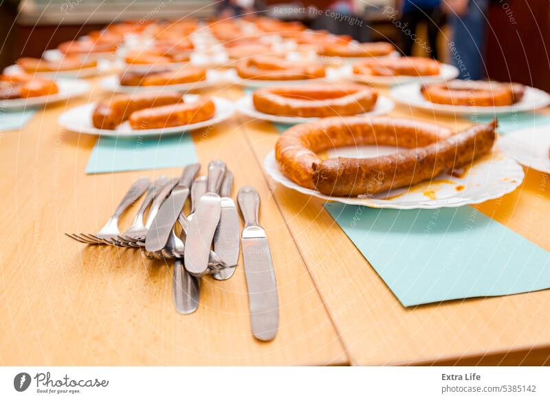 Stapel von Besteck vor gegrillten und frischen handgefertigten Würsten auf weißem Teller für Wurstturnier arrangiert angeordnet gewichten gebacken Bratwurst