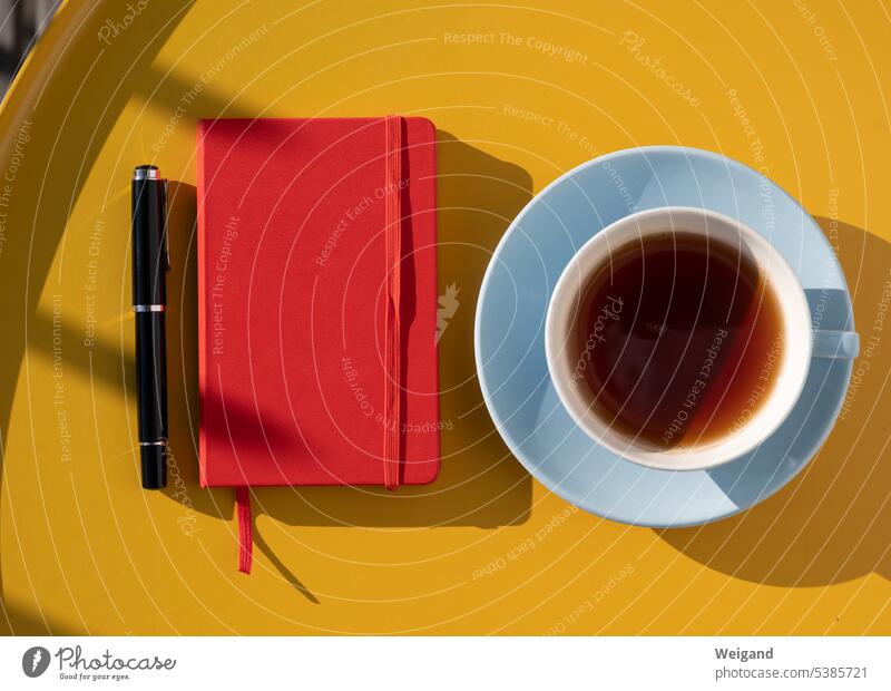 Notizbuch auf einem gelben Tisch mit einer hellblauen Tasse Planen Ideen Startup Ordnung Klarheit Konzept Ruhe Tee Achtsamkeit Stille Pause Sommer rot Memoiren