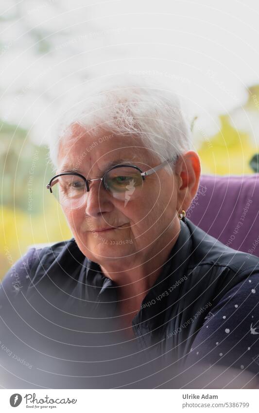 Mainfux |Glückliche Seniorin Rentnerin graues Haar Brille konzentriert lesen Frau Schmunzeln Zufrieden Porträt zufrieden älter positiv Lächeln Freude heiter