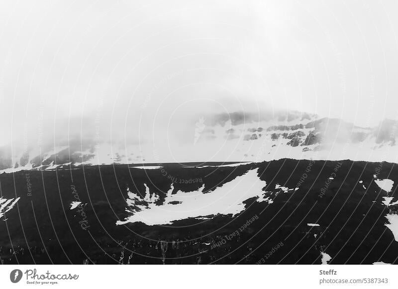 Bergseite mit bizarren Schneeformen auf Island isländisch bizarre Formen Schneereste Nebelschleier unheimlich Islandstrolle mysteriös Schneeformation