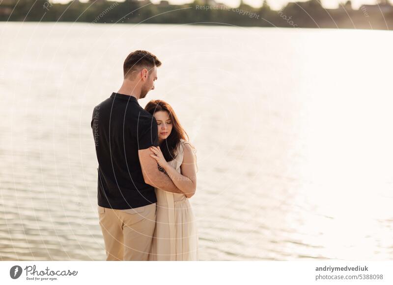 Romantisches Paar umarmt im Freien. elegante und stilvolle Frau und Mann in der Liebe sind zu Fuß entlang des Sees. Glückliche Momente zusammen. Liebesgeschichte
