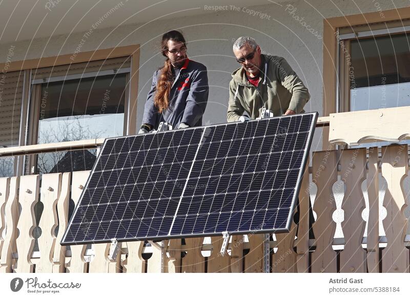 Zwei Männer montieren ein Balkonkraftwerk zur Gewinnung von Strom balkonkraftwerk solar stromerzeugung stromerzeugen haus solarmodule montage männer arbeiter