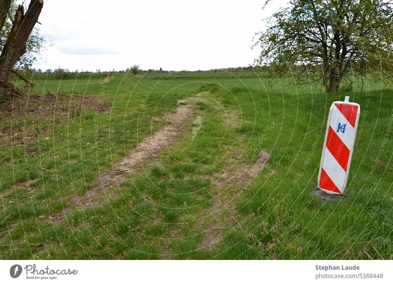 An einem Feldweg auf einem ehemaligen Rieselfeld bei Teltow (Potsdam-Mittelmark) warnt eine rot-weiße Bake vor einer Kurve Warnung Verkehrszeichen Vorsicht