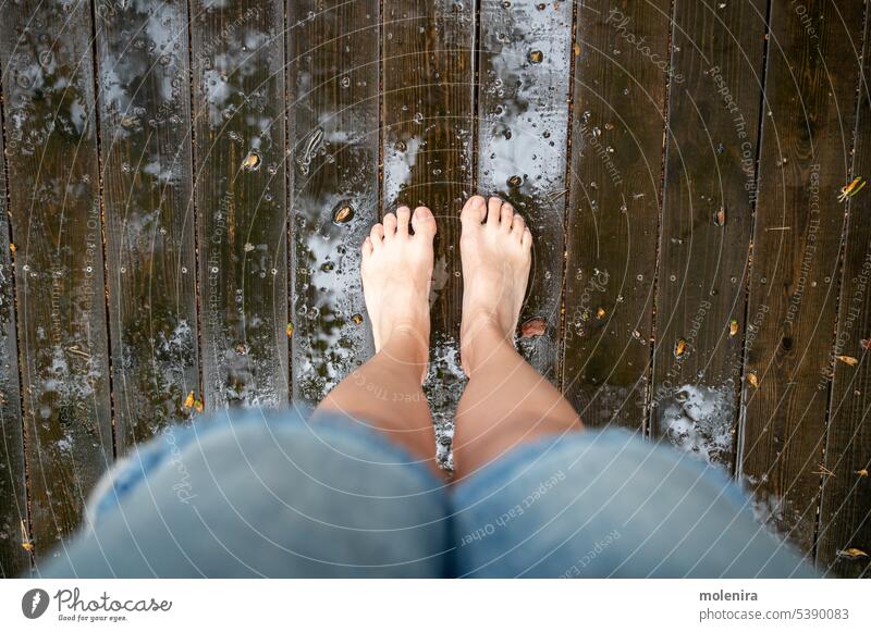 Die Beine einer Person stehen auf dem nassen Holzboden einer Terrasse Barfuß patio Regen Tropfen hölzern Stock Haus Schiffsdeck außerhalb Wasser Hinterhof