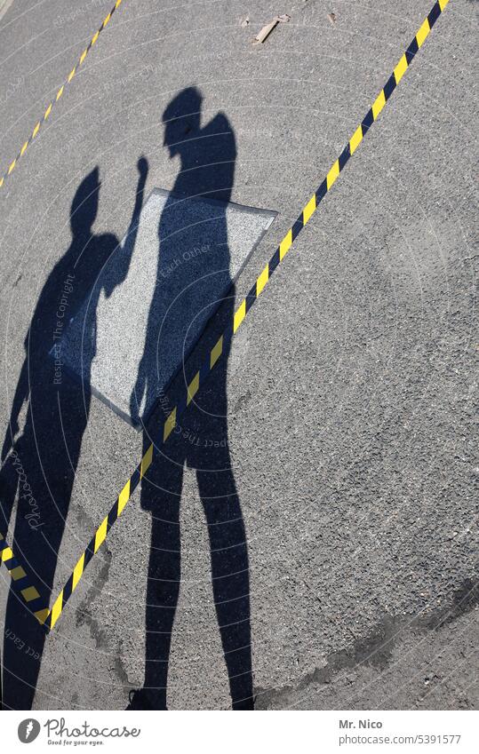 Schattenboxen Silhouette Schattenspiel Asphalt Straße absperrband flatterband signalstreifen kennzeichnung markierung absperrung absperren schwarz-gelb