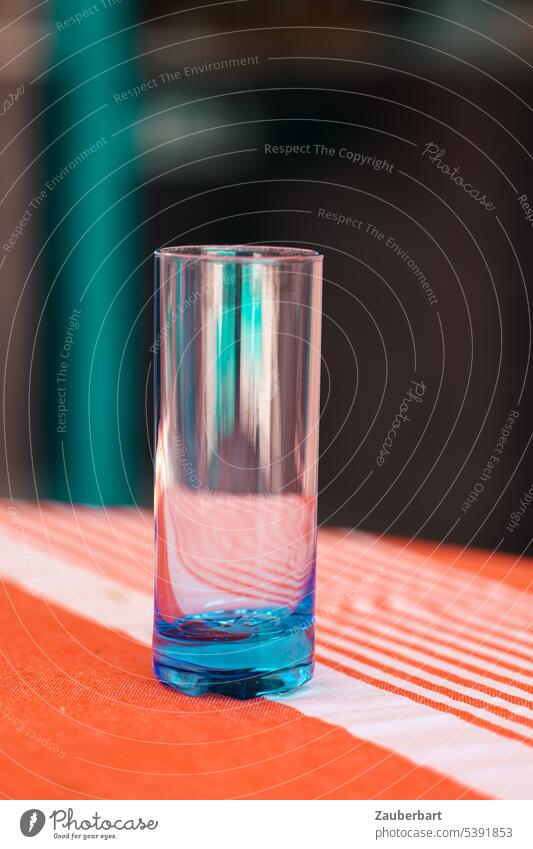 Leeres Wasserglas in blau auf Tischdecke mit orangefarbenen Streifen, Objekt oder Stillleben Glas grün Spiegelung rein trinken Trinkwasser leer frisch