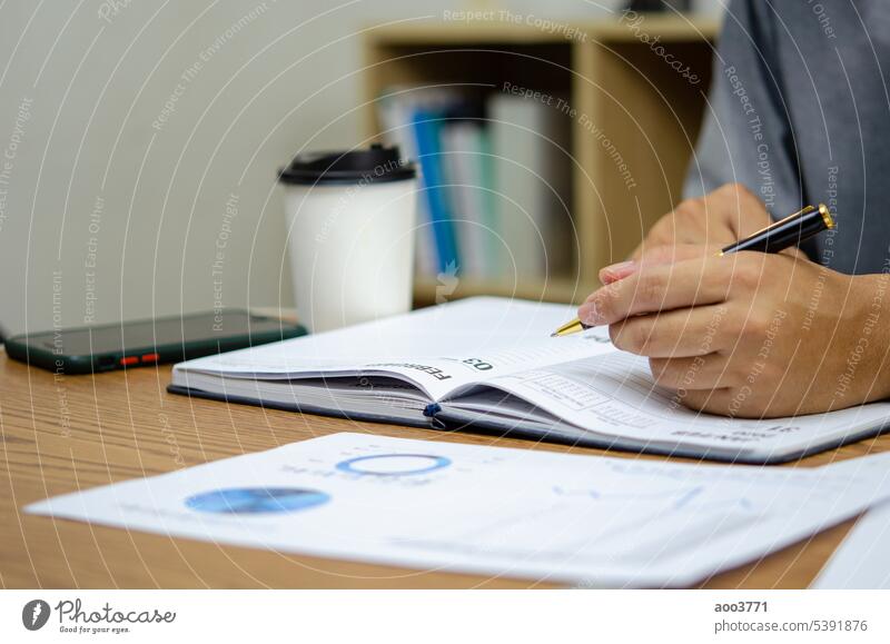 Geschäftsmann mit Stift schreiben Notizbuch Planung Journal und Analyse Informationen Statistiken Dokument auf dem Schreibtisch. schreibend Papier Schriftstück