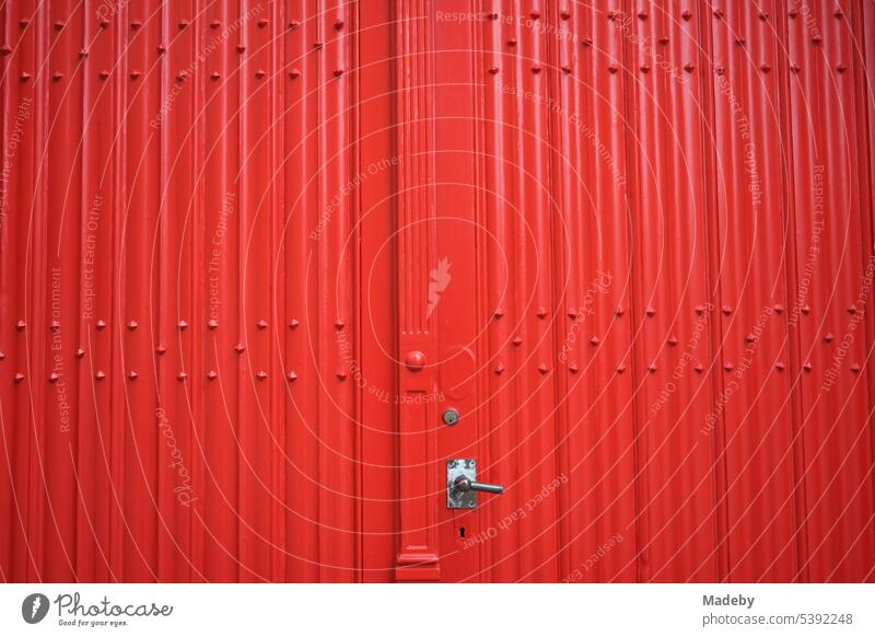 Schönes altes Tor einer Garage oder Einfahret in Rot mit silbernem Griff in den Gassen der Altstadt von Brügge in Westflandern in Belgien beschaffenheit wand