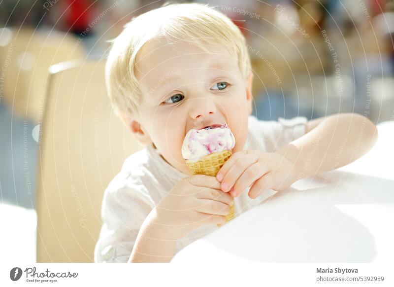 Niedlicher kleiner Junge isst Eis in einer Waffelwaffel. Kind probiert Gelato in italienischem Café. Ungesundes Fast Food auf der Straße. Eiscreme Essen wenig