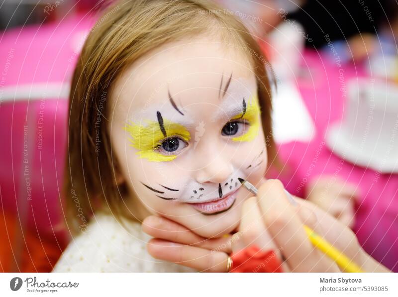 Gesichtsbemalung für niedlichen kleinen Gorl bei Kinderbelustigung. Gesichtsbemalung für "Tiere" Thema auf Geburtstagsparty. Vorschulkinder feiern eine Party im Unterhaltungszentrum.