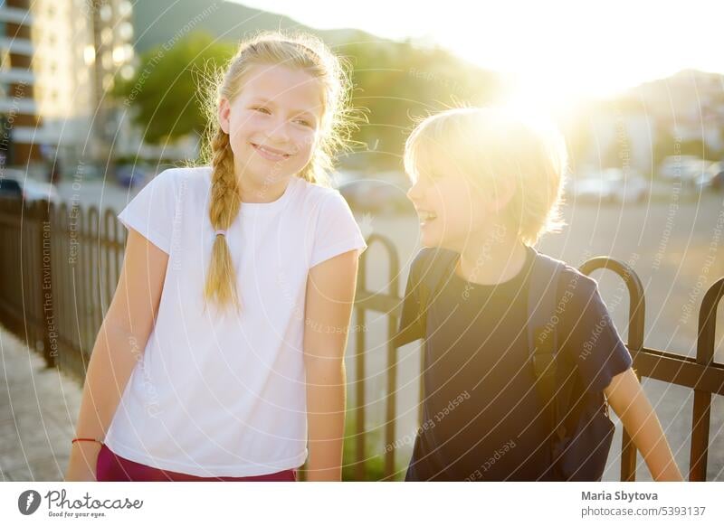 Porträt eines glücklichen Mädchens und eines Jungen im Teenageralter auf einer Straße in der Stadt während eines Sonnenuntergangs im Sommer. Die Freunde gehen zusammen spazieren. Erste Liebe