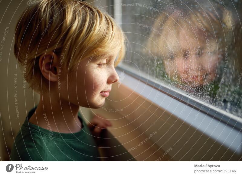 Porträt eines Jungen im Teenageralter, der am Fenster steht. Kind beobachtet den Regen draußen. offen Hoffnung Liebe Art herzhaft sichere Regulierung Fähigkeit