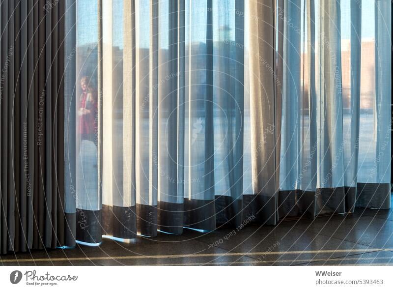 Durch den Vorhang und das große Fenster sieht man jemanden vorübergehen durchsichtig transparent Gardine Falten Faltenwurf Sichtschutz Aussicht beobachten Frau