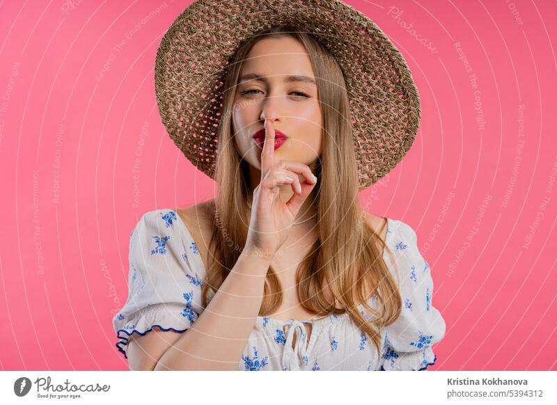 Lächelnde Frau mit Finger auf den Lippen - shhh, Geheimnis, Stille, rosa Studio Hintergrund fragen beißend charmant Nahaufnahme Konzept Verschwörung
