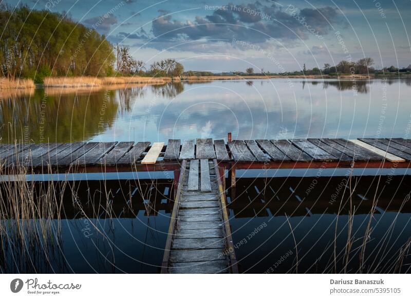 Ein Steg aus Holzplanken auf einem ruhigen See Windstille Pier Wasser hölzern im Freien Himmel friedlich blau Feiertag Natur schön Brücke Landschaft Sommer