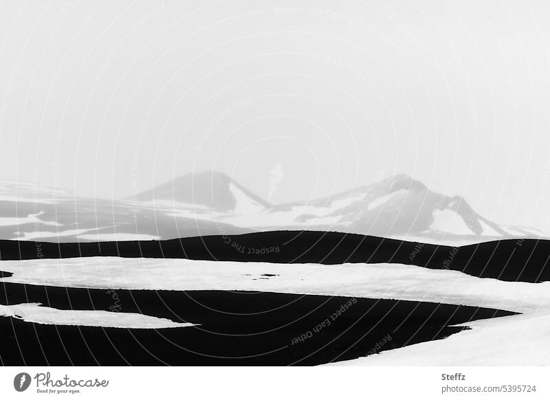 Schneelandschaft mit den Bergen und Hügeln auf Island Nordisland Schneeschmelze abstrakt kalt felsig weiß schwarz schwarzweiß einsam grau dunkel geheimnisvoll