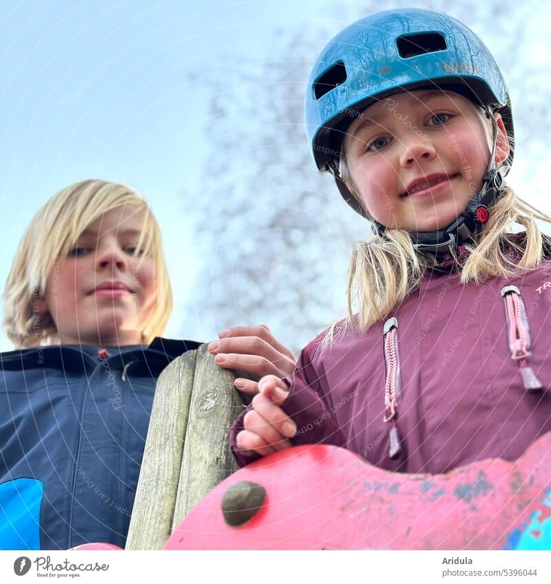 Doppelportrait | Zwei Kinder schauen von einem Klettergerüst herunter Junge Mädchen Spielplatz Fahrradhelm Porträt Portrait Kindheit Spaß Freude im Freien