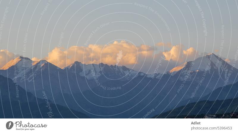 Die schneebedeckten Berge von Trans-Ili Alatau werden bei Sonnenaufgang von der Morgensonne beleuchtet Berge u. Gebirge Morgendämmerung Cloud Schnee Himmel