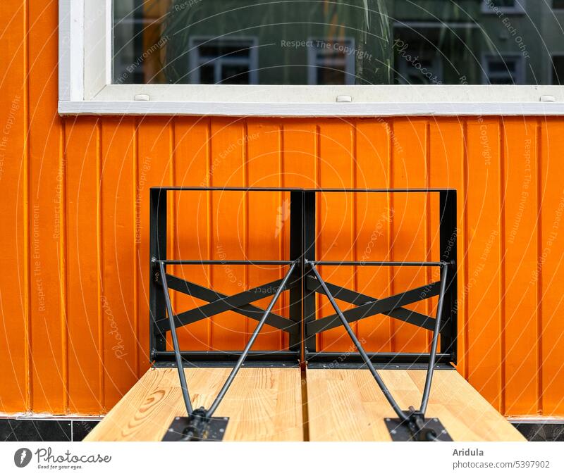 Außengastronomie | Hochgestellte Bierbänke vor orangener Holzwand mit Fenster Gastronomie Restaurant geschlossen Wand Biergarten Bierbank Bank Sitzgelegenheit
