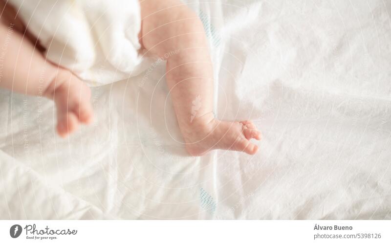 Die kleinen Beine und Füße eines Neugeborenen in einer Windel, in der Krippe, zu Hause Baby neugeboren verfrüht Ansicht subjektiv kleine Füße kleine Finger