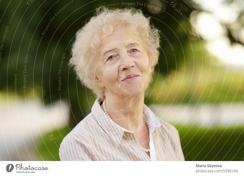 Outdoor-Porträt der schönen älteren Frau mit lockigem weißen Haar Senior Dame Gesundheit Gesicht wirklich Holunderbusch Lifestyle Vitalität positiv Rentnerin