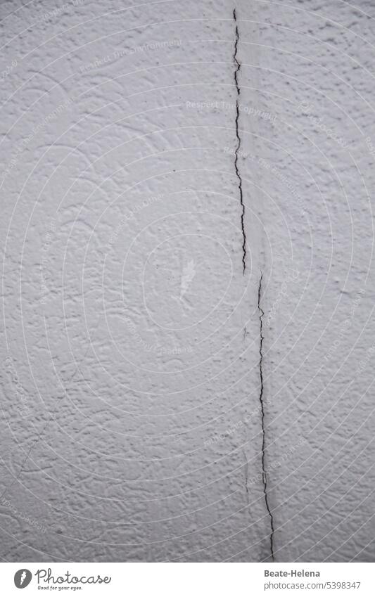 Hauswand mit Riss - "es geht ein Riss durch Deutschland" Wand weiß Struktur vertikal Detailaufnahme Material Oberfläche alt rau abstrakt Muster verwittert