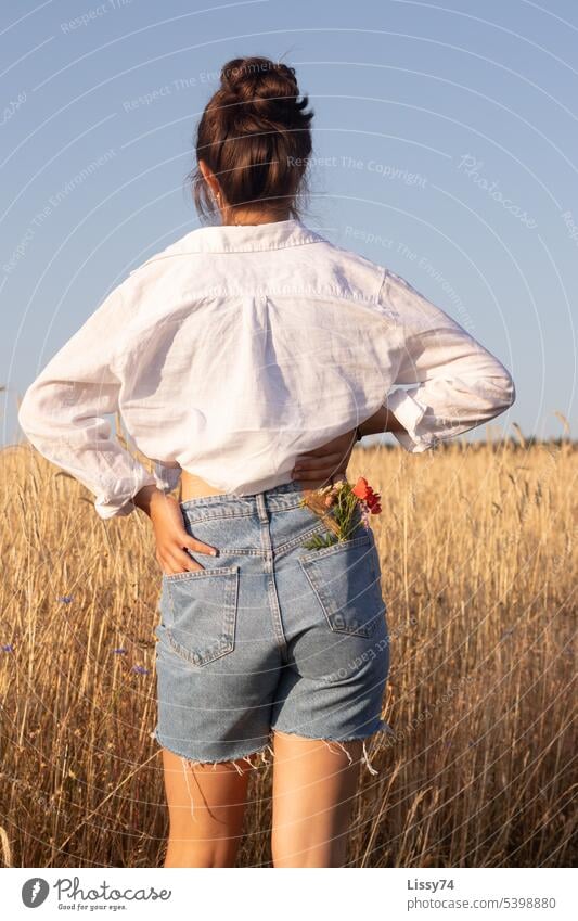 Am Feldrand stehendes Mädchen mit einem Blumenstrauß in der Hosentasche 2.0 Natur Sommer Getreidefeld natürlich natürliches Licht Jeansshorts jeans bunt