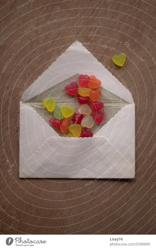 Viele bunte Gummibären-Herzen schauen aus einem Briefumschlag heraus Gummibärenherzen naschen Süßigkeiten Süßwaren süß Symbole & Metaphern Flatlay bunt gemischt