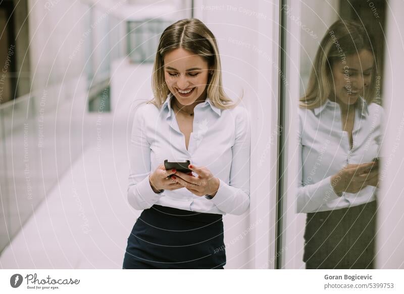 Junge Geschäftsfrau, die im Büroflur ein Mobiltelefon benutzt Frau Kaukasier professionell Business Flur Menschen Telefon Person selbstbewusst sprechend