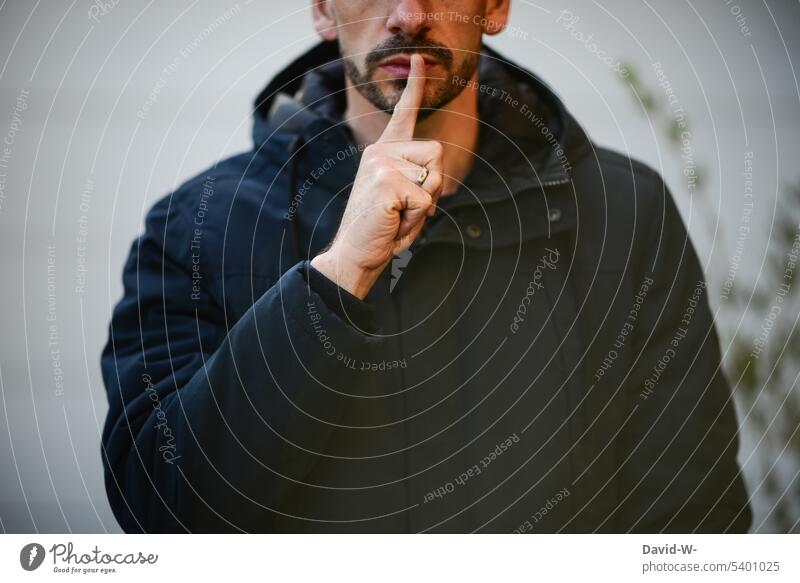 Pst - ruhig sein - Mann mit Finger vor dem Mund Schweigen ruhe Aufforderung pst leise Lippen anonym