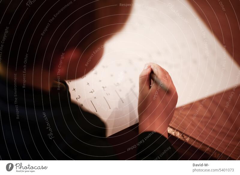 Kind beim lernen rechnen Hausaufgaben Schule Bildung Stift rechenaufgabe Mathematik Junge schreiben Hand Tisch Schreibtisch Zettel ausrechnen nachdenklich