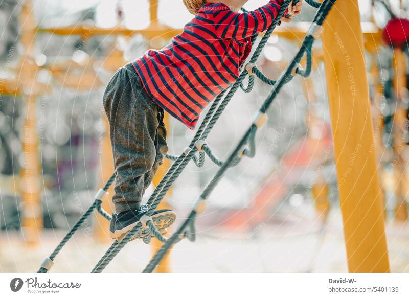 Kind klettert auf dem Spielplatz Klettern Klettergerüst Spielen spass mutig erkunden Junge Klettermax