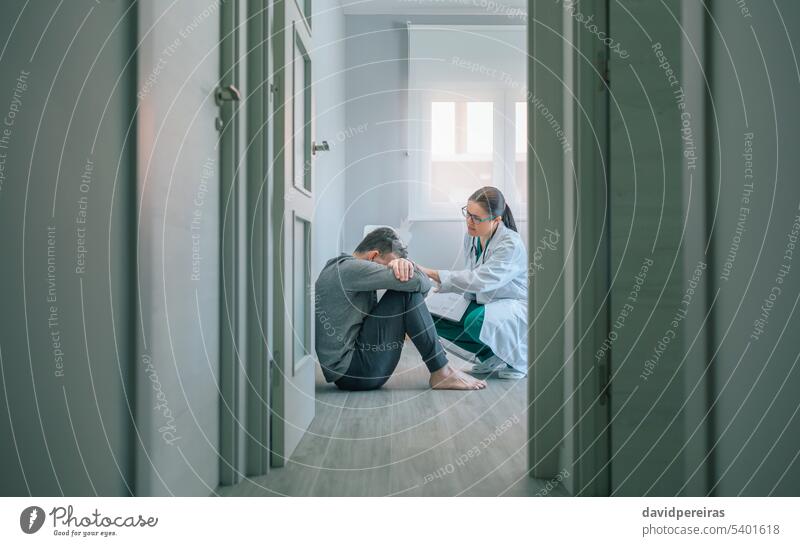 Arzt beruhigt und hilft dem auf dem Boden sitzenden Patienten Frau Hilfe beruhigend Einfühlungsvermögen mental Gesundheit Erkrankung sprechend geduldig Sitzen