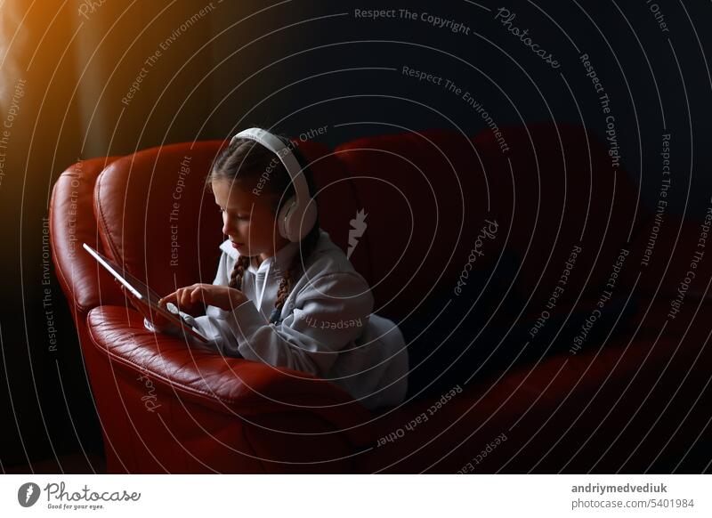 Konzentrierte Teenager-Mädchen in Kopfhörer spielt Spiel, kommunizieren im Internet Social Media, hört Musik oder Online-Studien zu Hause auf digitalen Tablet sitzen auf dem Sofa. Kinder Tech-Sucht Konzept