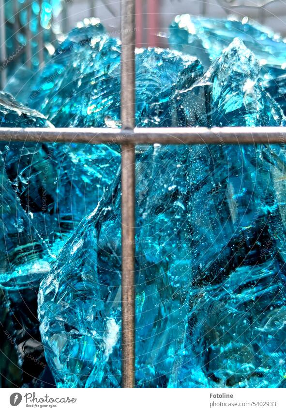 Von Metallstreben werden Glasklumpen gehalten, die aussehen wie Eis. Blau und klar. Licht blau eisblau hellblau Klumpen Glassteine Sonnenlicht Metallstange