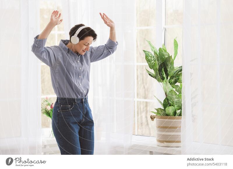 Frau hört Musik im Wohnzimmer zuhören sich[Akk] entspannen Kopfhörer zu Hause Freizeit Vergnügen benutzend heimwärts Lebensmitte Melodie lässig Gesang Gerät