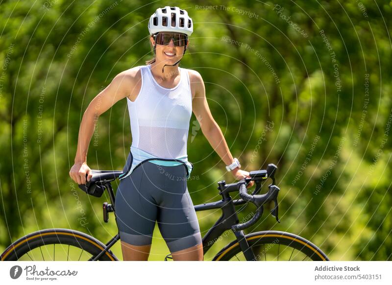 Sportlerin mit Fahrrad vor verschwommenem Park Athlet Schutzhelm Sonnenbrille Sportbekleidung passen Porträt Frau Radfahrer Aktivität dynamisch Herz Training