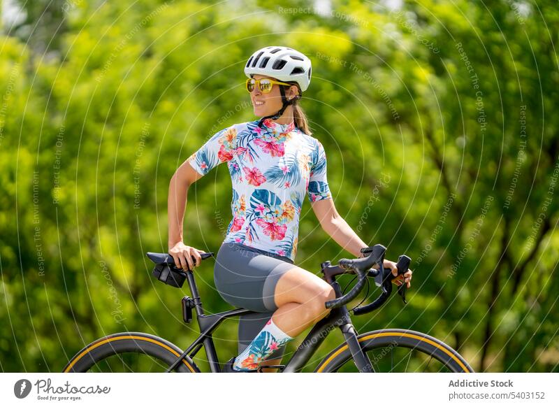 Sportlerin auf Fahrrad gegen verschwommenen Park Radfahrer Schutzhelm Sonnenbrille Sportbekleidung passen bewundern Sommer Frau Athlet Rennfahrer Sicherheit