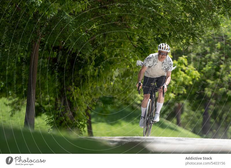 Sportler auf dem Fahrrad auf dem Lande vor unscharfem Hintergrund Radfahrer Mitfahrgelegenheit Schutzhelm Sonnenbrille Straße Park Sommer männlich Athlet aktiv
