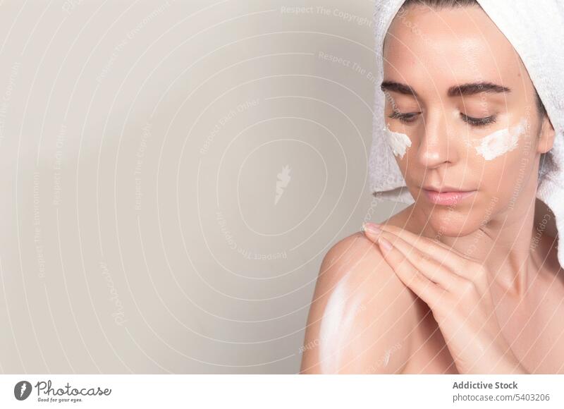 Ernste junge Frau trägt Feuchtigkeitscreme auf die Schulter auf bewerben Hautpflege Sahne Schliere Schönheit Routine Handtuch Kosmetik Verfahren