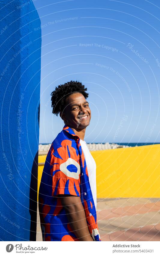 Glücklicher junger Mann in stilvoller Kleidung heiter Hemd positiv Wand urban froh Outfit Stil Lächeln schwarz Afroamerikaner männlich Inhalt ethnisch