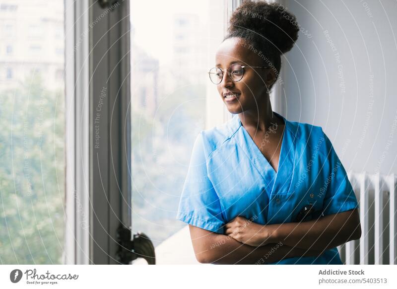 Inhalt Afroamerikanische Ärztin steht am Fenster Frau arzt Arzt Sanitäter Praktiker medizinisch Gesundheitswesen nachdenken Lächeln Uniform Dame Brille