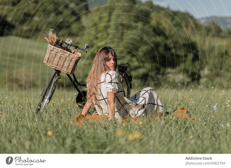 Ernste junge Frau mit Fahrrad auf grasbewachsenem Feld ruhen Gras Landschaft Wochenende Natur sich[Akk] entspannen genießen sitzen friedlich lässig sorgenfrei