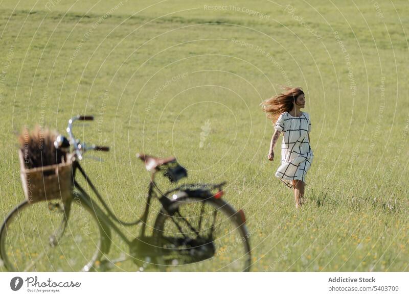 Frau spaziert sorglos auf grüner Wiese mit wehendem Wind Fahrrad Park Feld Sommer Natur Spaziergang Abenteuer aktiv Aktivität jung allein genießen sorgenfrei