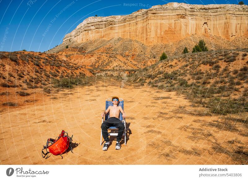 Jugendlicher auf Klappstuhl in der Wüste sitzend Junge Bräune Ausflug Tourist Sonnenbad Stoffstuhl Stuhl Sonnenbrille Reisender Teenager Schlucht