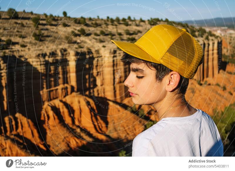 Nachdenklicher Junge mit Mütze, der über einer Bergschlucht steht Natur Landschaft Schlucht nachdenklich Tourist Ausflug Berge u. Gebirge Augen geschlossen