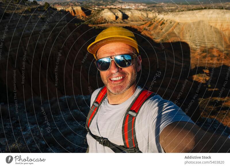 Glücklicher männlicher Wanderer mit Sonnenbrille macht ein Selfie auf einer felsigen Klippe Mann Reisender Schlucht Lächeln Porträt Selbstportrait rojo teruel