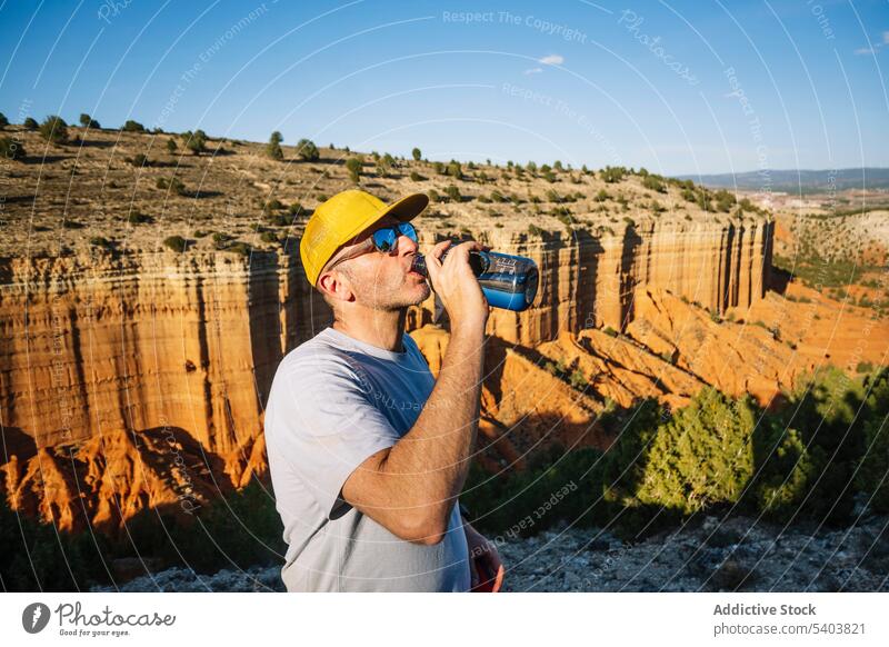 Mann trinkt Wasser aus einer Flasche, während er an einer Klippe steht Schlucht trinken Tourist Berge u. Gebirge Erfrischung rojo teruel Spanien Abenteuer