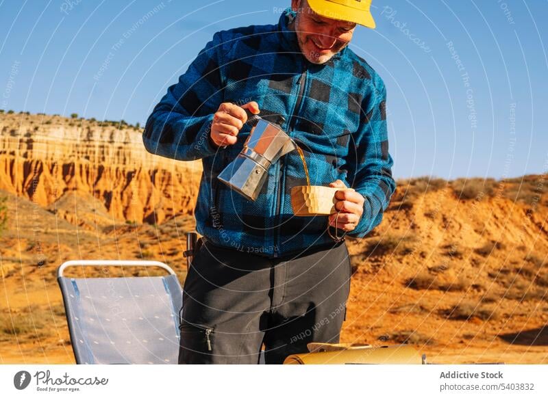 Glücklicher Mann gießt Kaffee aus einem Kessel in der Natur ein Reisender heiter Wasserkessel Schlucht Moka-Topf Tourist eingießen Lächeln Porträt Landschaft