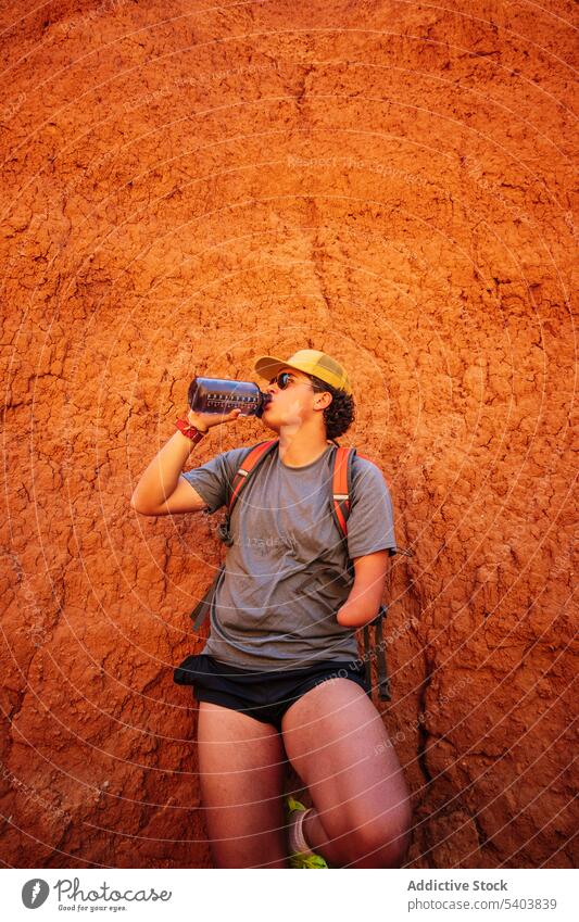 Junger männlicher Amputierter mit Wasser während eines Wüstentrips Mann trinken Schlucht ruhen Wanderer Durst Pause Aktivität Klippe Tourismus Flasche Urlaub